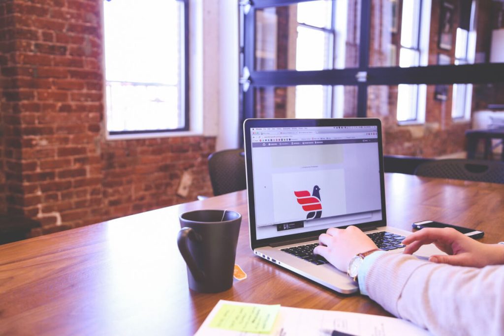 person working on laptop in office with large windows