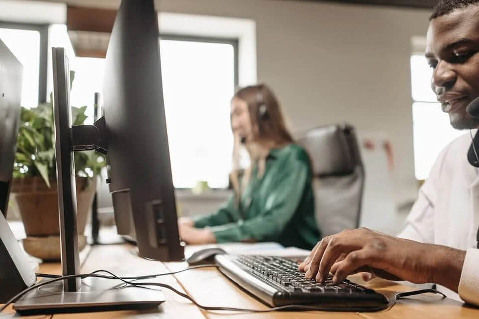 two colleagues seated next to each other, working on computers